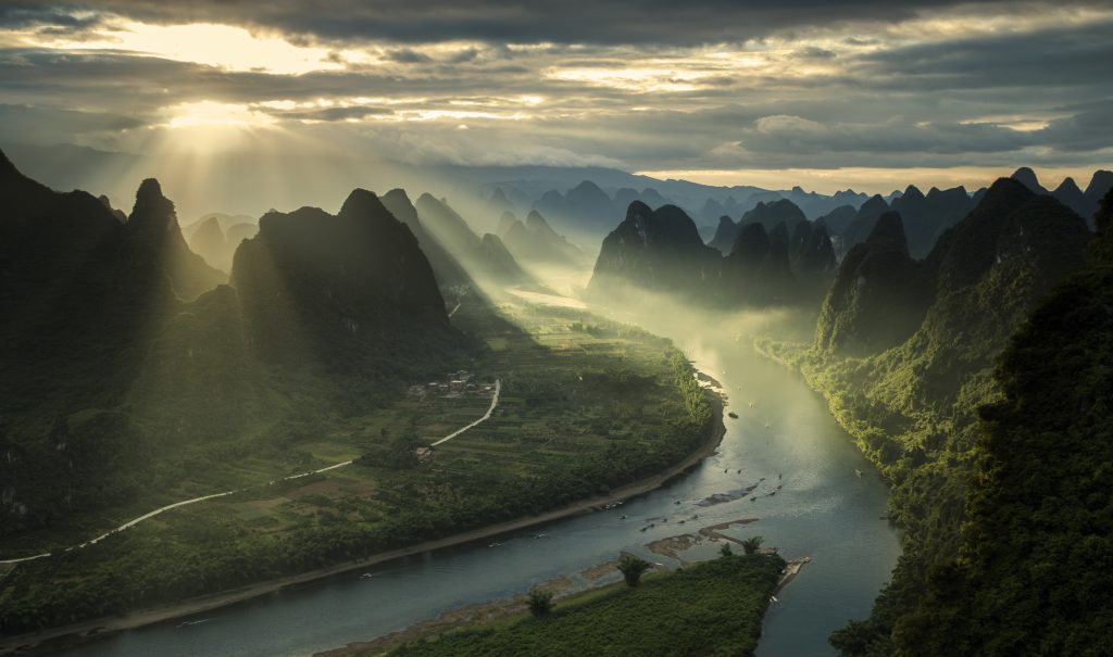 Sun beams on a misty morning on karst mountains and river